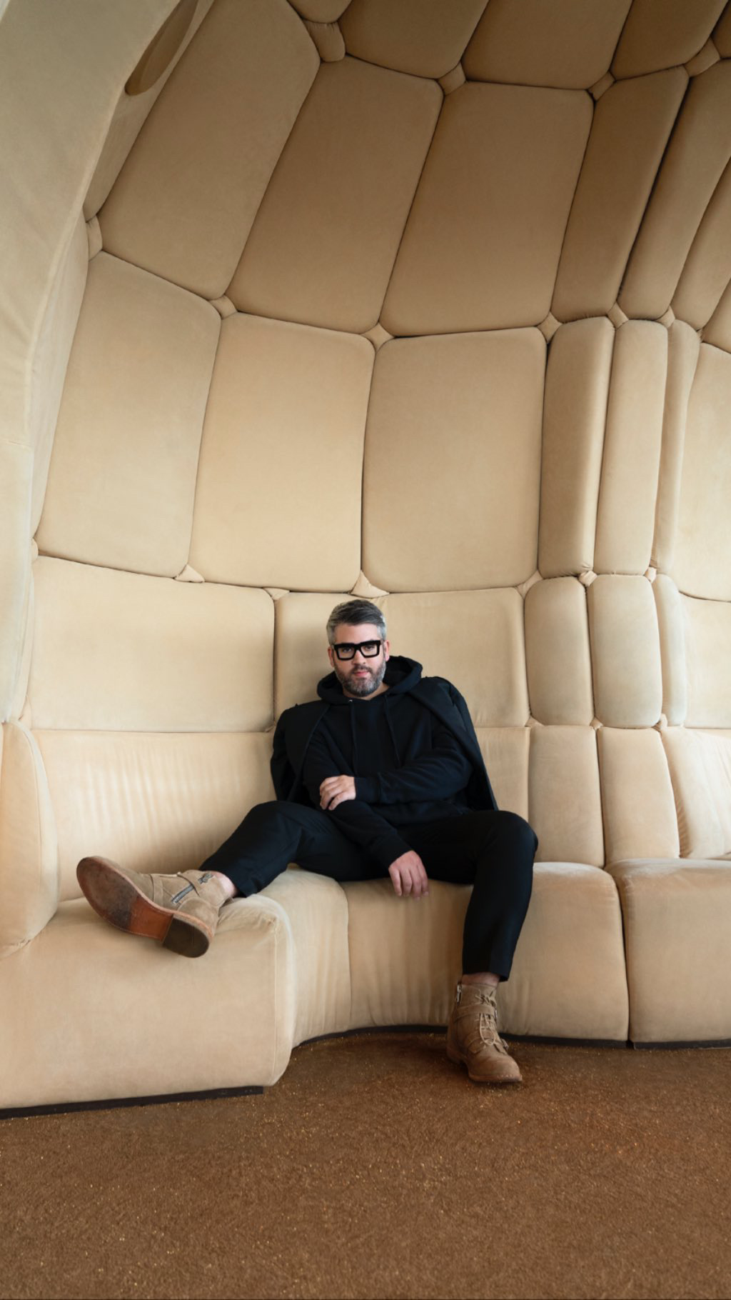 Brandon Maxwell seated in a cream padded room