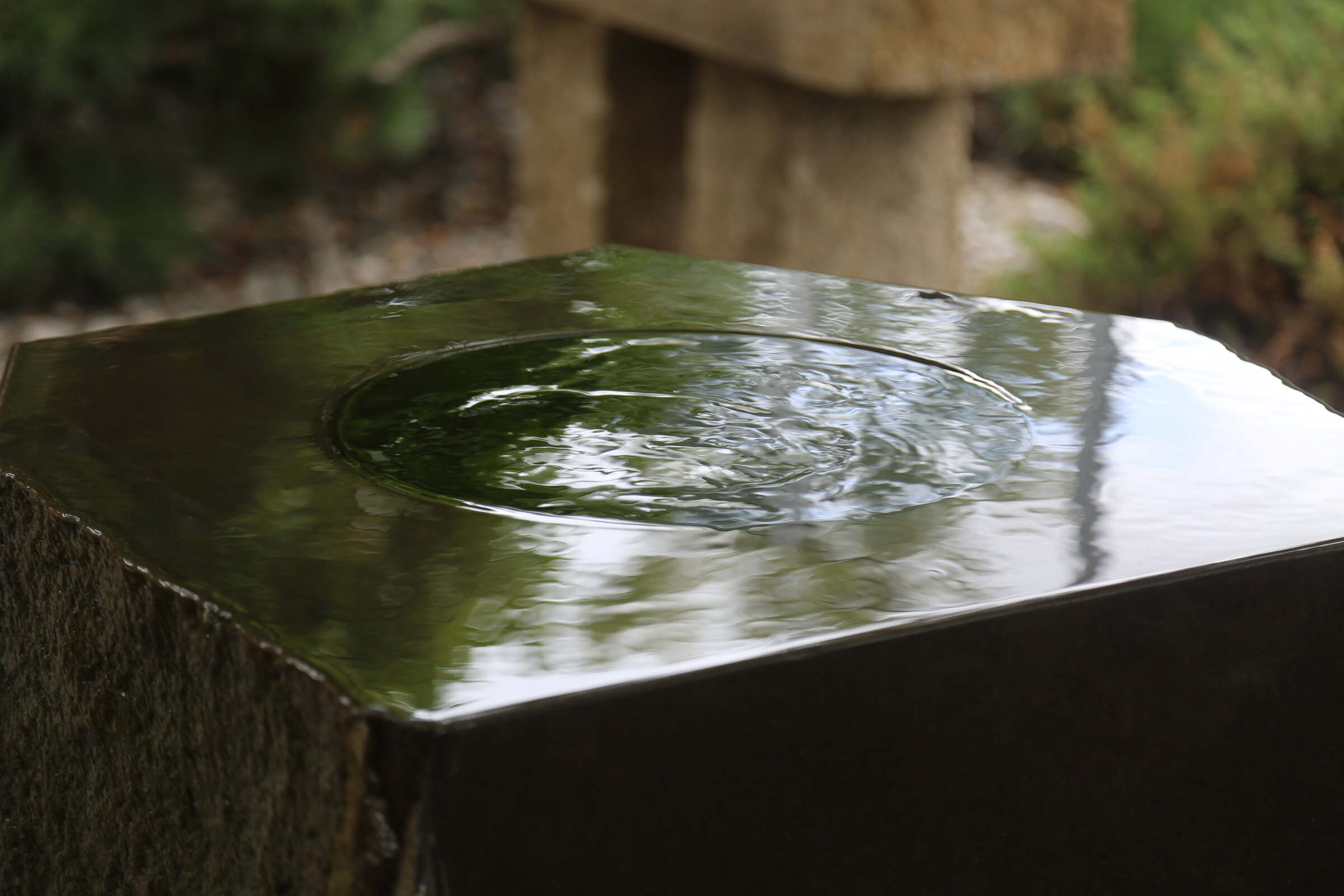 Rippling water across the polished surface of a dark stone sculpture