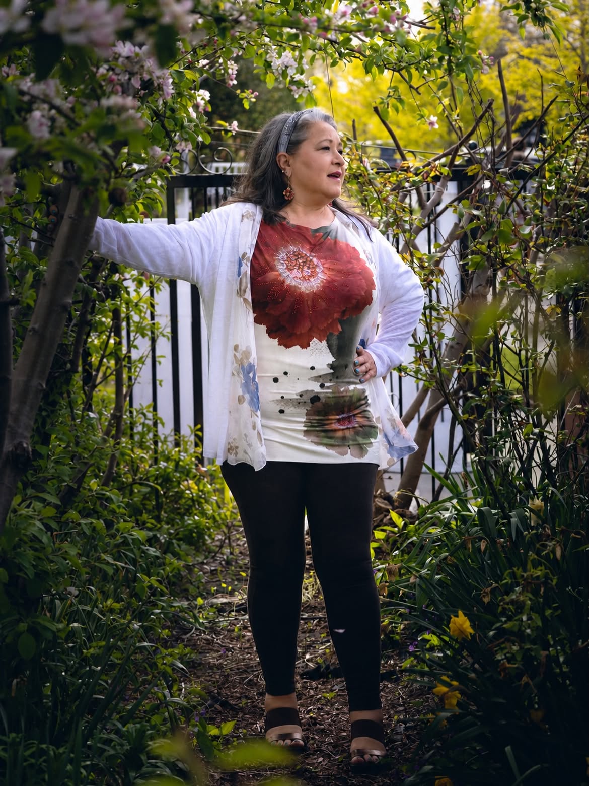 Paula Curci standing beneath flowering branches in a garden