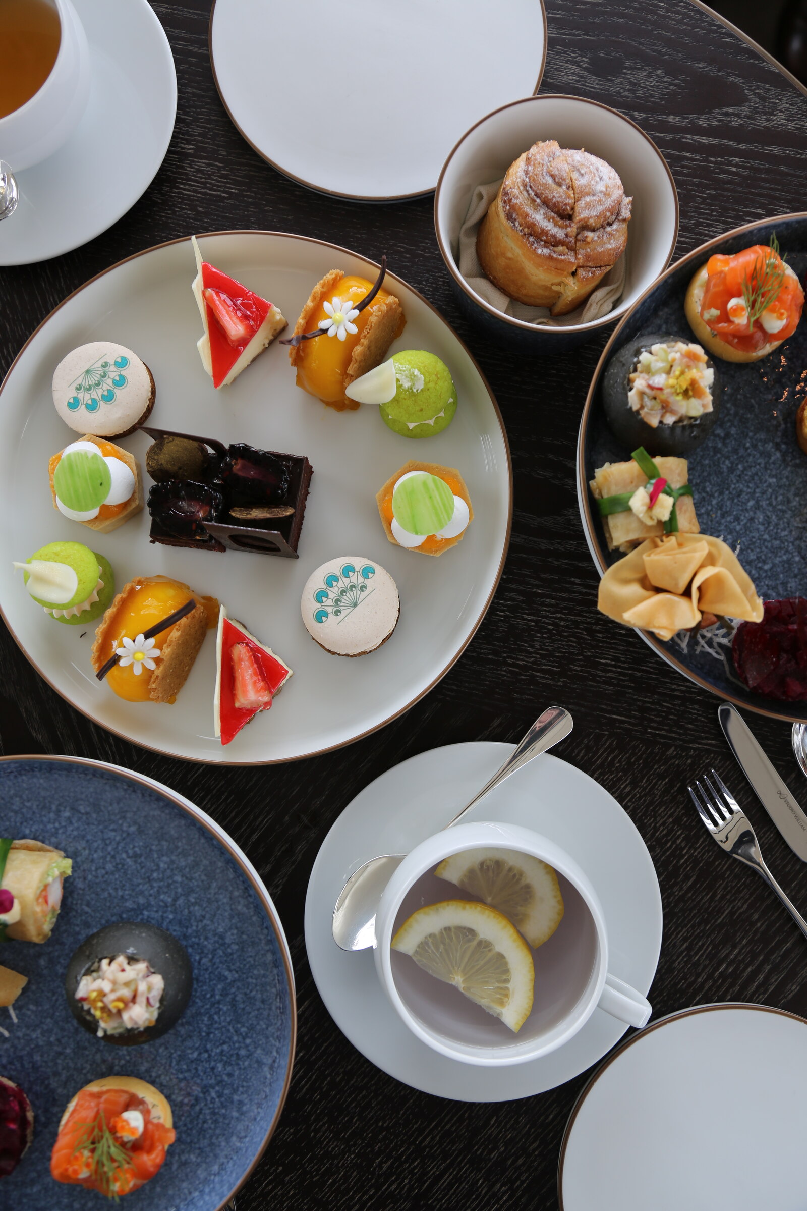 Overhead view of afternoon tea pastries, savory bites, and lemon tea at Waldorf Astoria Bangkok