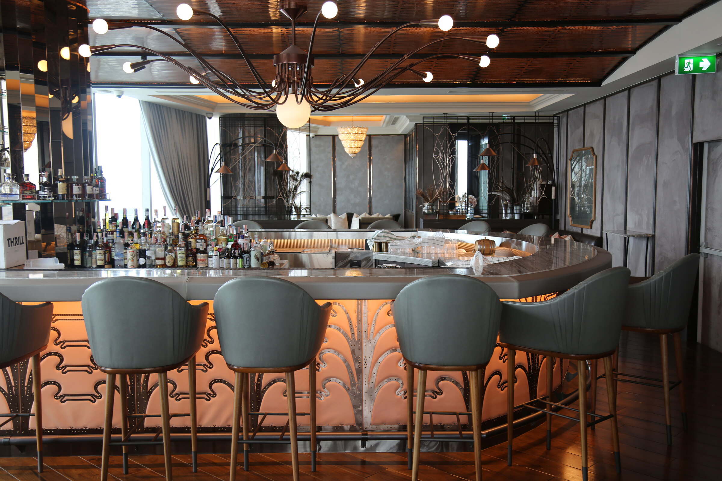Champagne Bar interior with a curved illuminated bar and sculptural lighting at Waldorf Astoria Bangkok