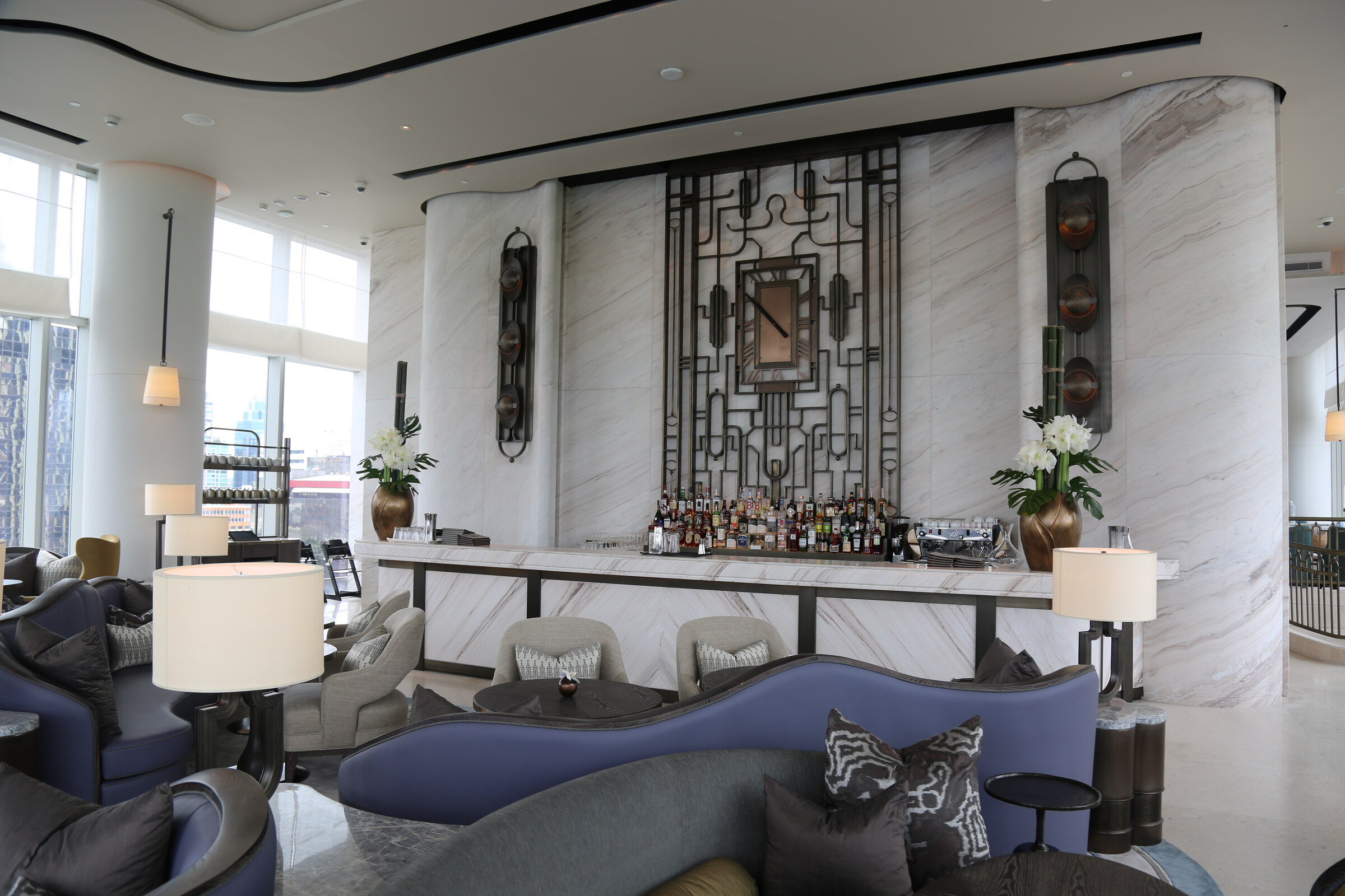 Clock Room lounge with marble bar, blue seating, and geometric metalwork at Waldorf Astoria Bangkok