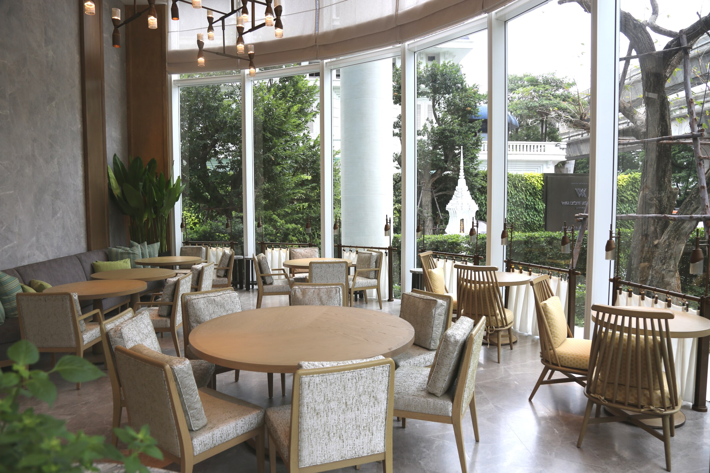 Garden Room dining area with curved windows overlooking greenery at Waldorf Astoria Bangkok