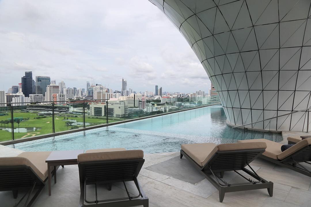 Infinity pool and lounge chairs overlooking the Bangkok skyline at Waldorf Astoria Bangkok